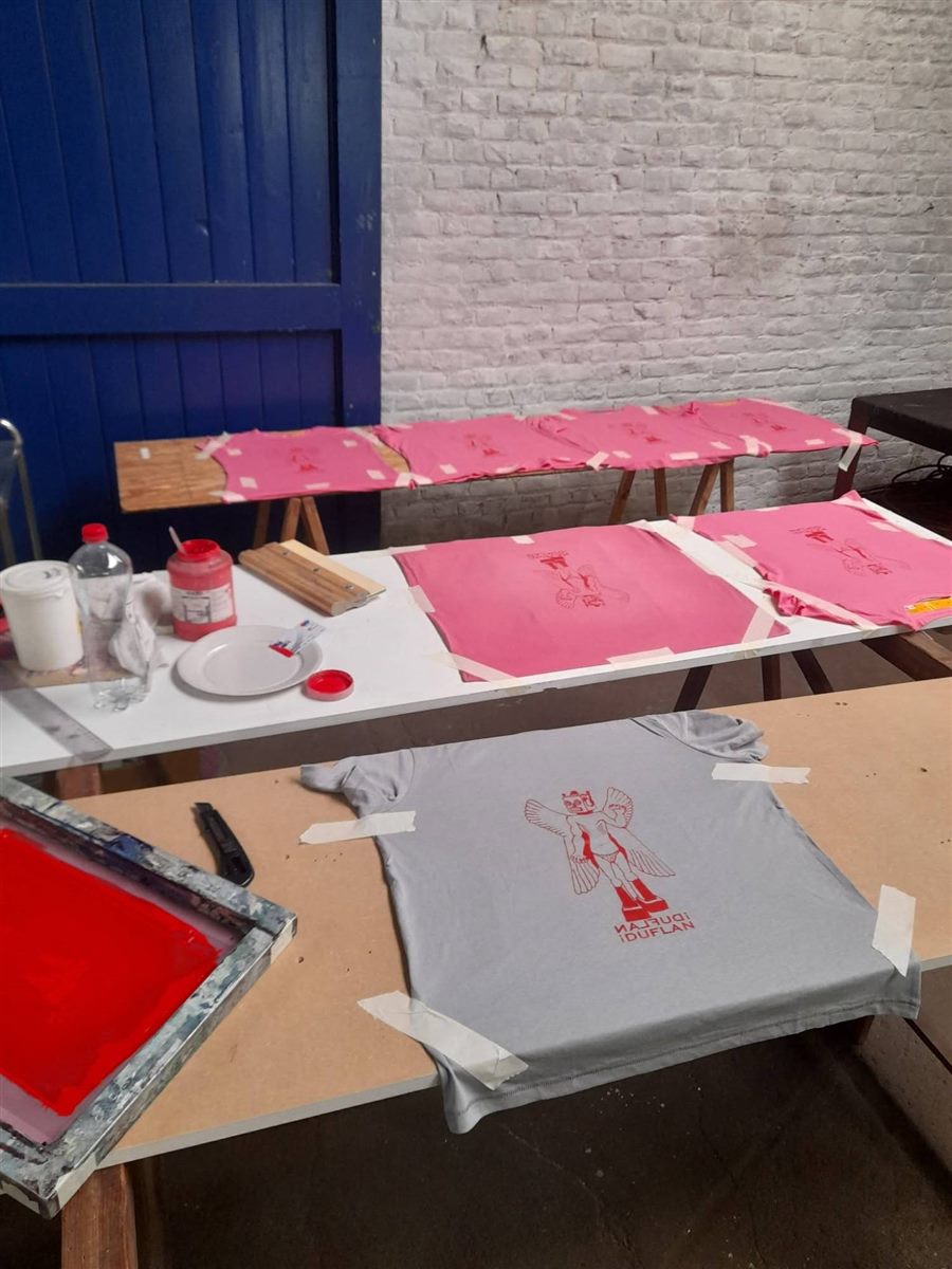 Sérigraphie maison des tee-shirts ¡ Duflan Duflan ! : tee-shirts roses et gris sur les tables, écran rouge